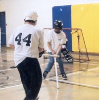Two athletes in front of goalie, two coaches in background