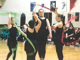 Four athletes demonstrate the group ribbon routine.